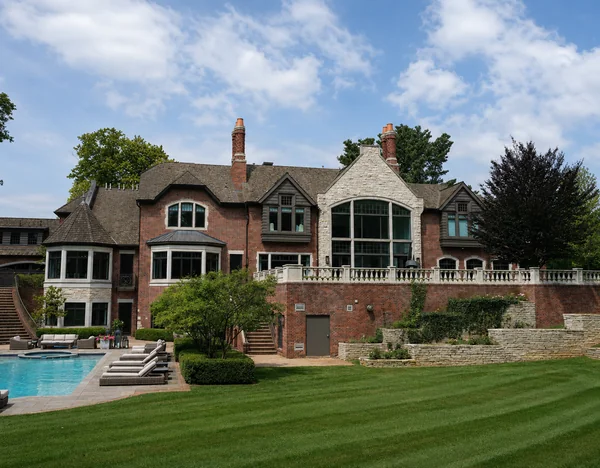 The rear of the house across the lawn in 2019, its brick reading as one even range from the terrace wall up to the gables