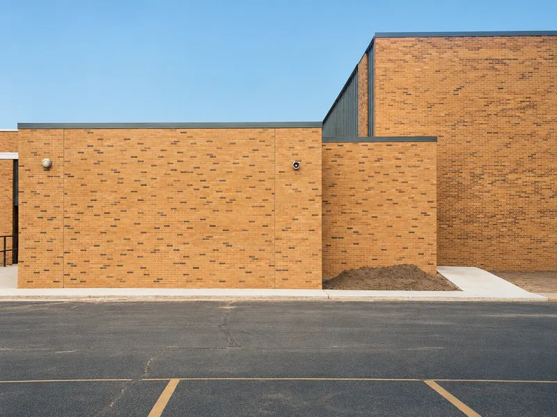 The same wall after staining, its brick now carrying the same blended range of dark units as the taller building behind it