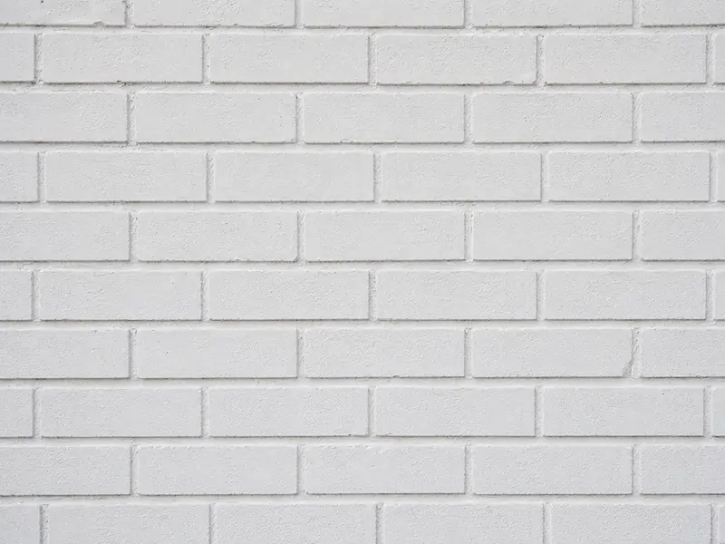 White brick wall soon after painting, the paint film still even and unbroken across every course