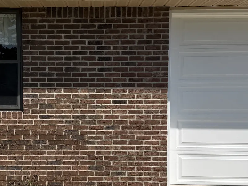 The same wall finished, every course from the window to the garage door carrying one even red brown