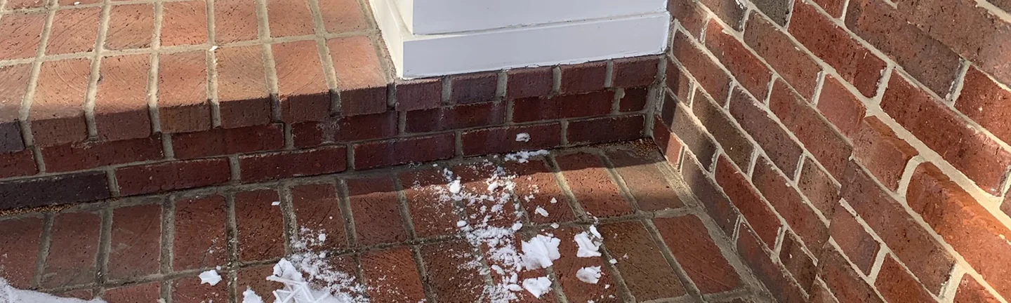 The porch pavers and top step at the base of a white column in 2021, one red range across the units