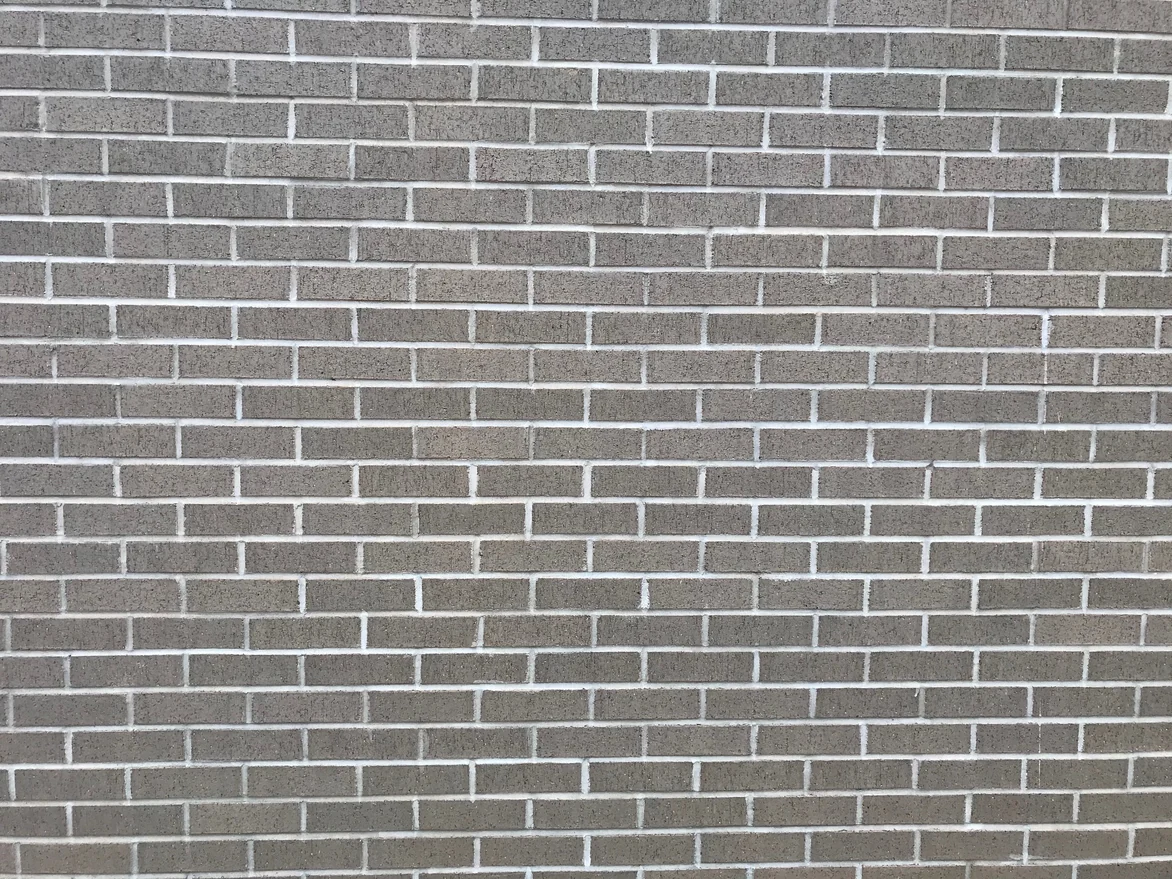 A stretch of the stadium brickwork in 2021 from a few feet away, grey-tan brick with every mortar joint the same pale grey