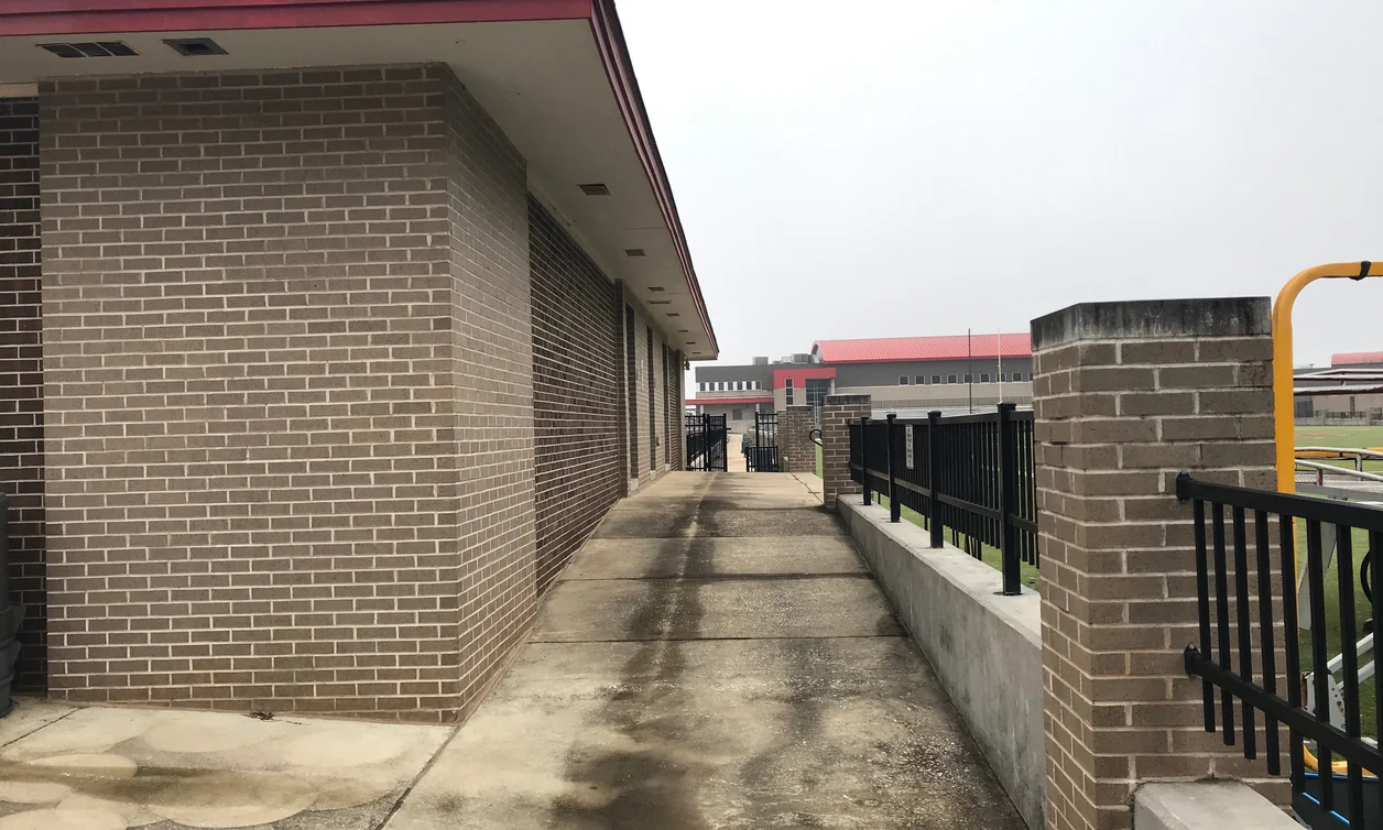 A brick stadium building along a walkway at an Alabama high school in 2021, its mortar one even color