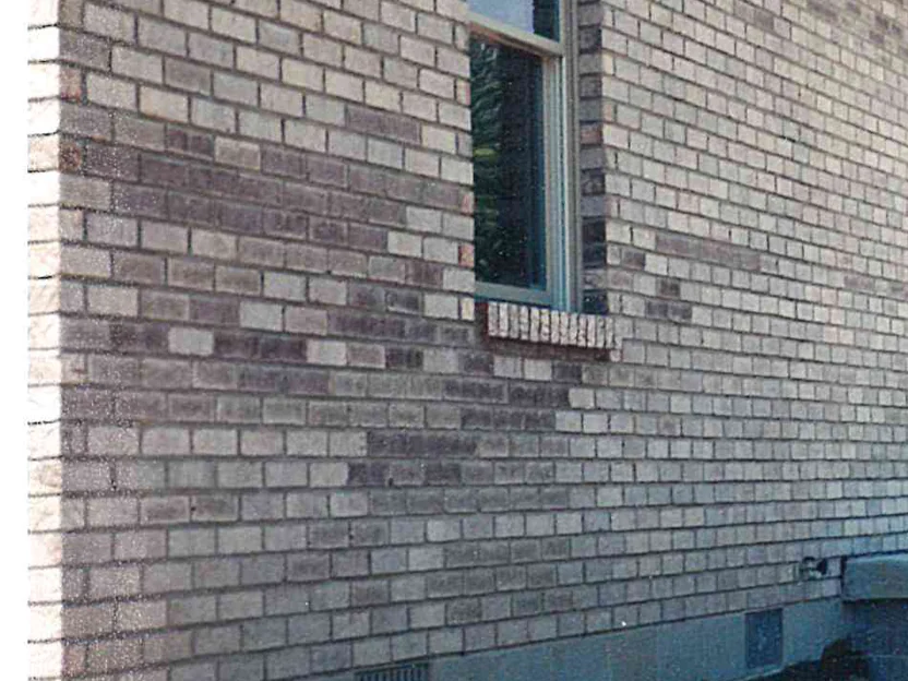 An outside corner in 2000, a tall narrow window above a rowlock sill with pale and grey brick patched unevenly across both walls