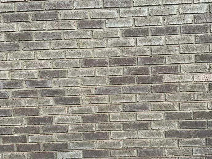 Close on the stained brick in 2019, grey, tan and mauve units alternating course by course with clean mortar joints