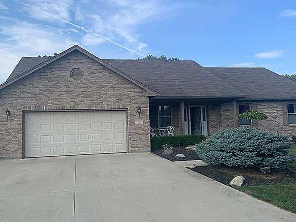 The front of the Arcanum house in 2019, buff brick running from the two-car garage past a covered porch