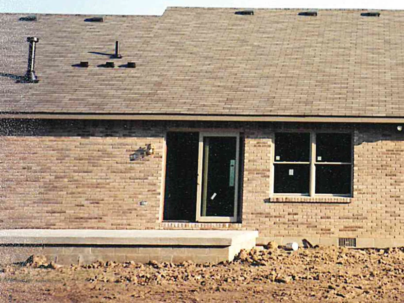 The same patio door wall in 2000 after staining, one even buff range from the concrete stoop up to the eaves