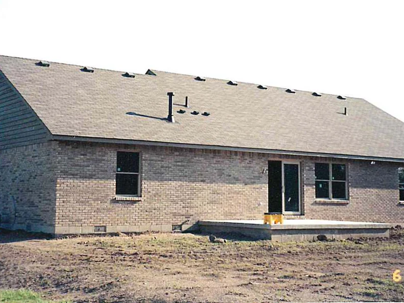 The same back wall in 2000 after staining, the brick reading as one warm tan range under the long shingled roof