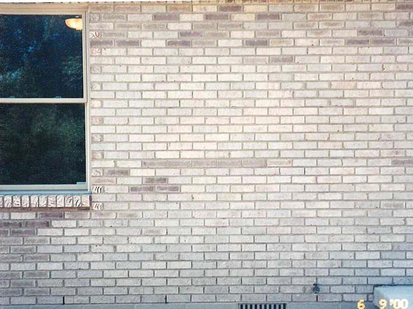 The wall beside a window in 2000, the brick faded to near white above a soldier course sill, with scattered darker units through the courses