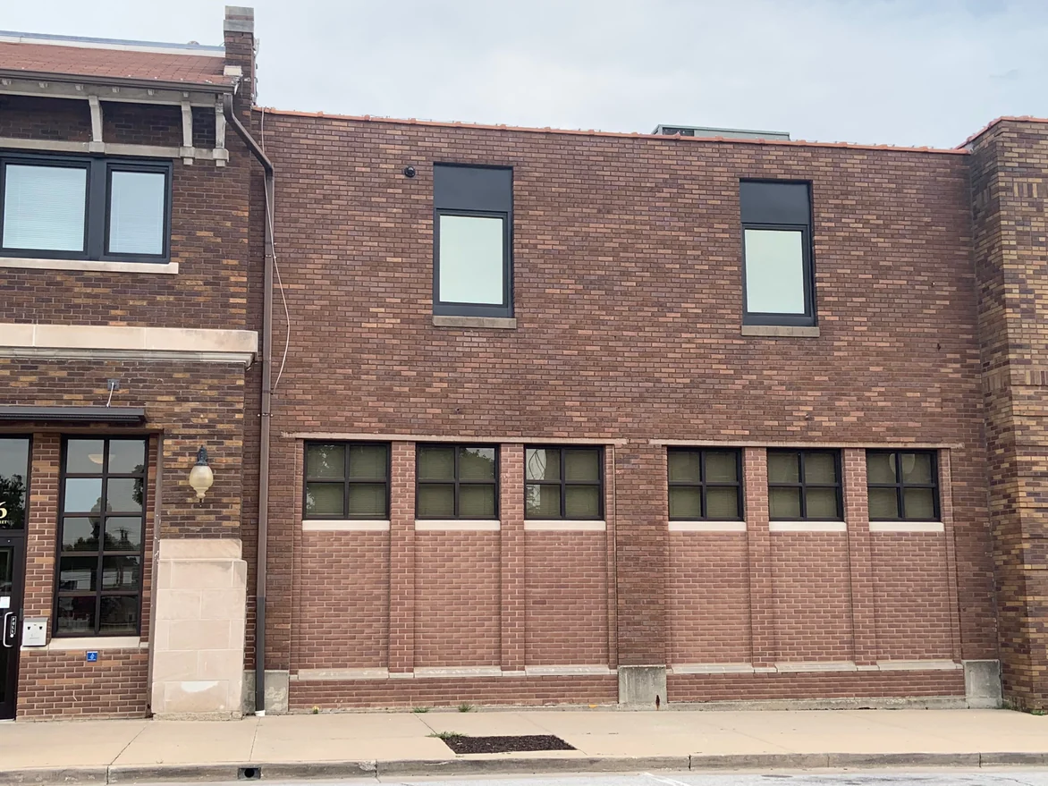The wing seen square on from the pavement in 2019, two storeys of brick reading as one range beside the older entrance block