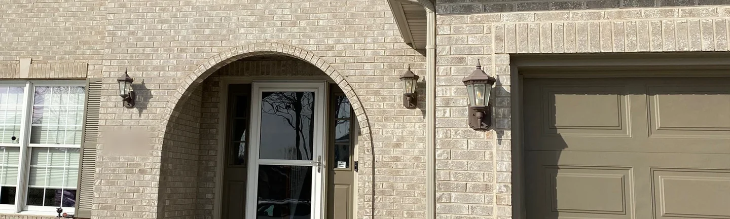 The front of the Aurora house in 2021, tan brick around an arched entry beside the garage, one range across the wall