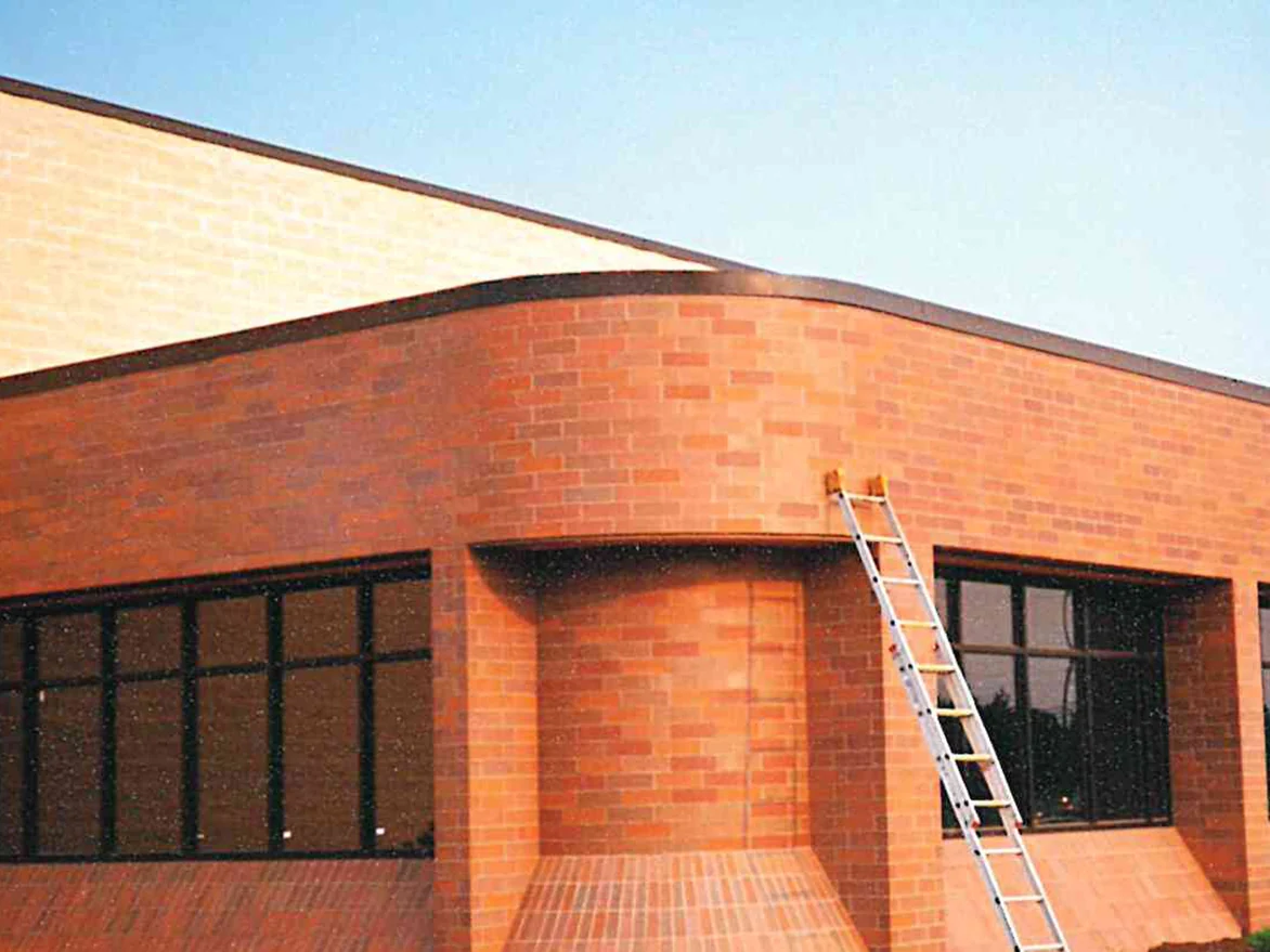 The curved corner of the same building later in 1997, the brick reading a deeper red brown around the recessed entrance, with a ladder against the wall and the ground still bare
