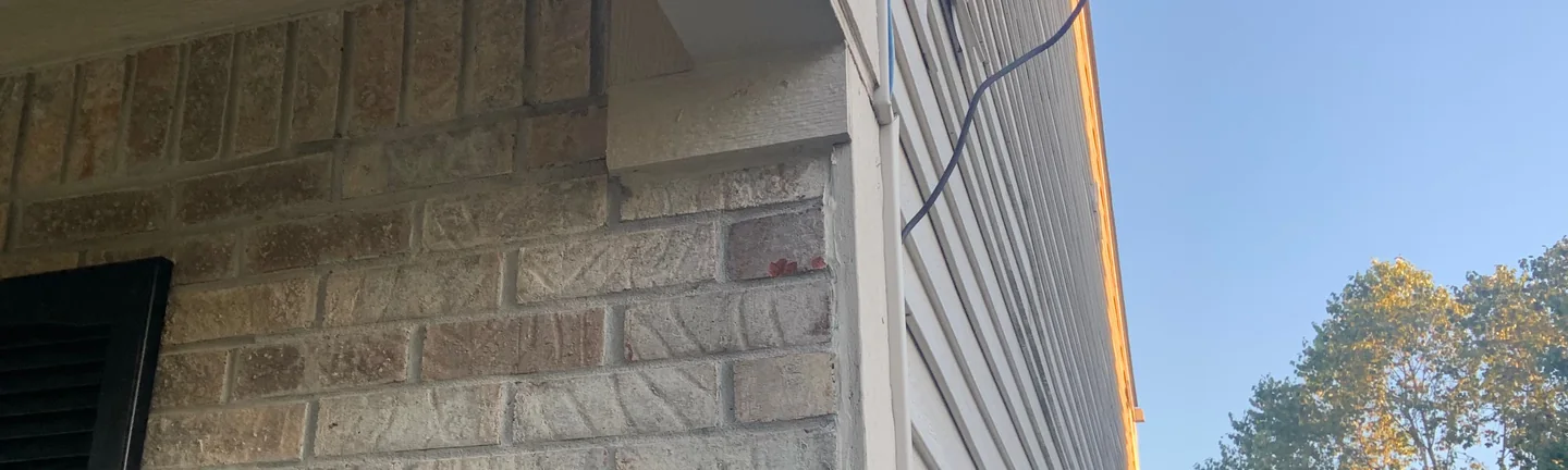 The outside corner of the Avon house in 2019, its brick reading as one buff and tan range where it meets white lap siding