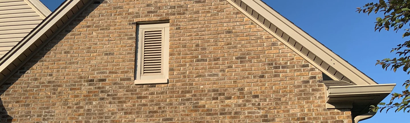 The brick gable of a two-story home in 2019, an even tan and brown range running up to the eaves