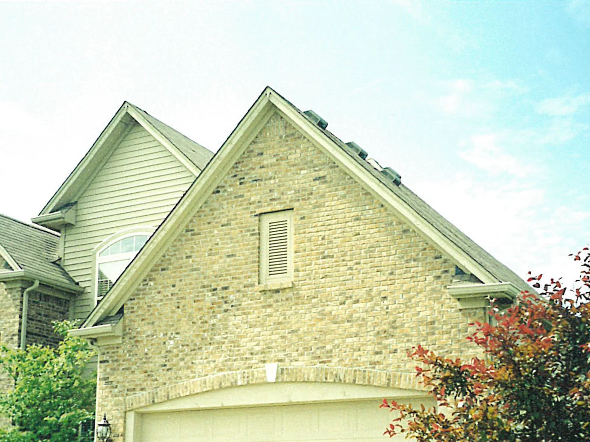 The gable end of a two-story home in 2003, its buff brick reading pale and washed out across the whole peak above the garage