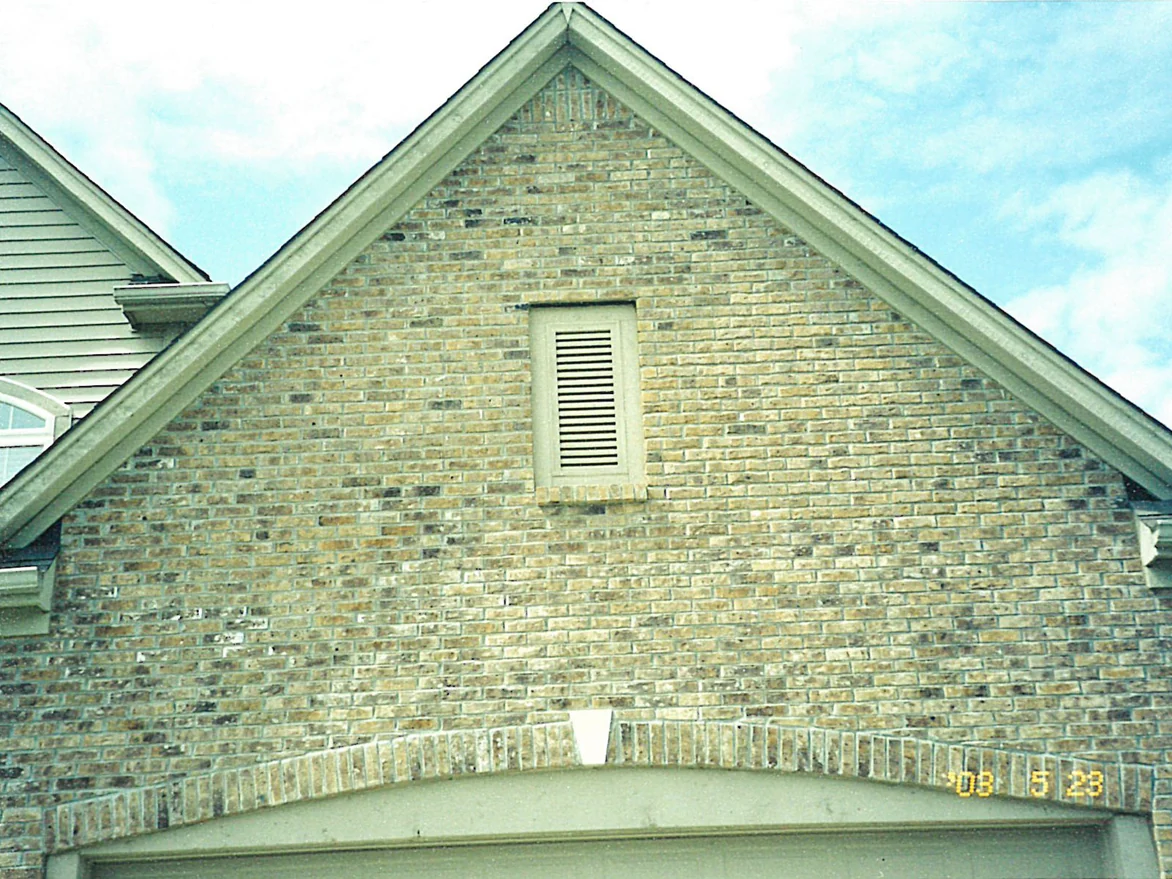 Close view of the same gable peak in 2003, near white units scattered through the tan brick around the attic vent