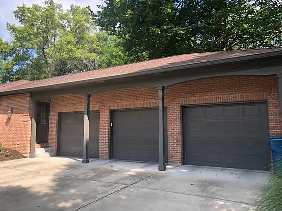 The three car garage wing of an Avon ranch house in 2019, its red brick reading as one even range under a low hipped roof