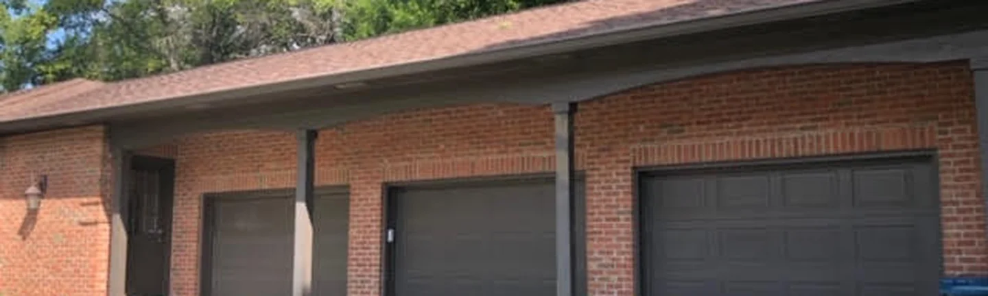 The garage wing of a single-story brick house in 2019, its red brick reading as one even range under a low hipped roof