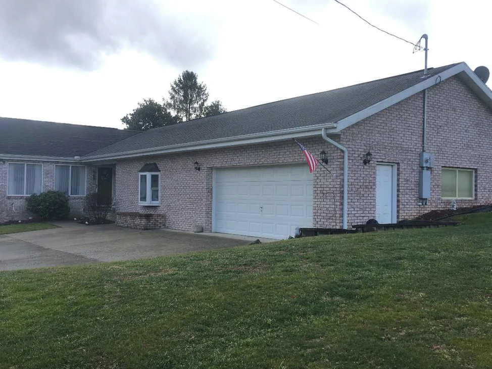 The front of the single-story Barboursville house in 2020, pale pink brick running from a bay window past the entry to a white garage door