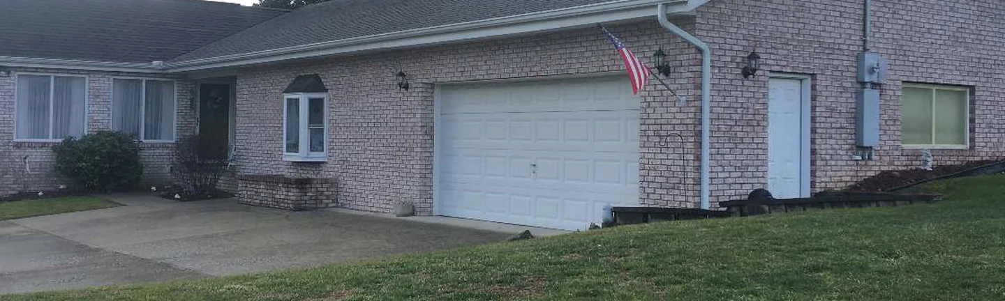 The front of the single-story Barboursville house in 2020, pale pink brick running from a bay window past the attached garage