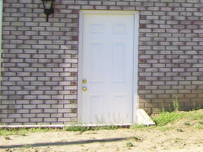 Close on the side door in 2008, a carriage lamp on the left and a course of darker red header brick running across above the opening