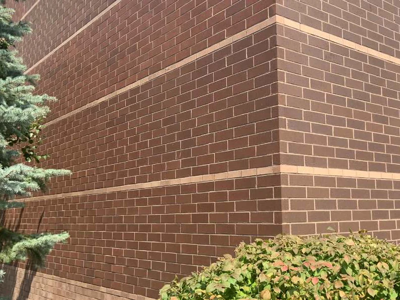 The outside corner in 2019 from close range, three cream accent courses carrying round the return with the red brown field brick even on both faces