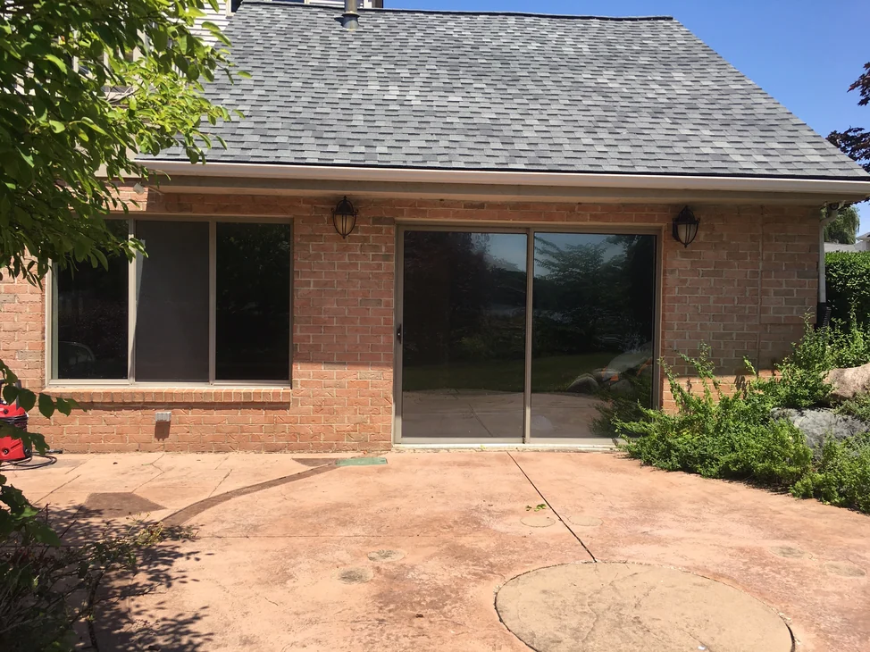 The rear wing of a Belleville house in 2019, its brick one even range of red and tan under a shingled gable, with a sliding door between two lanterns.