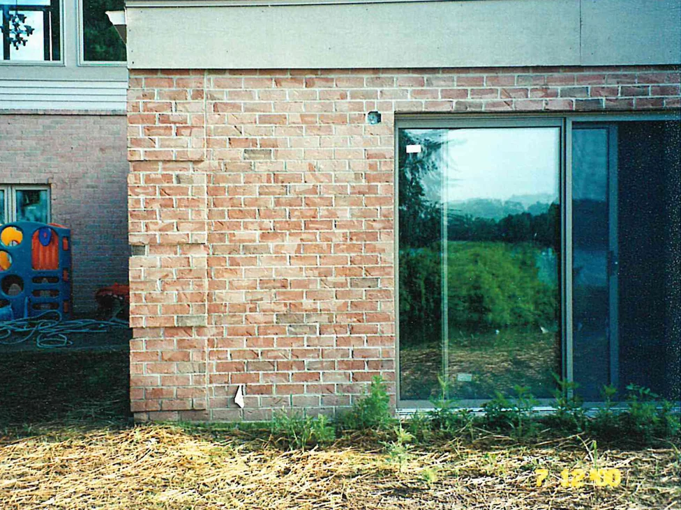 A rear wall part way through the work in 2000, some courses carrying warm color again while the units beside them stay pale and mottled