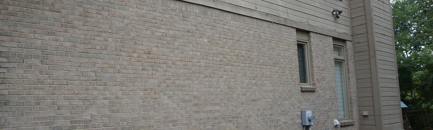 The long brick side of the Bloomfield house in 2019, reading as one even buff wall from the corner to the gable end