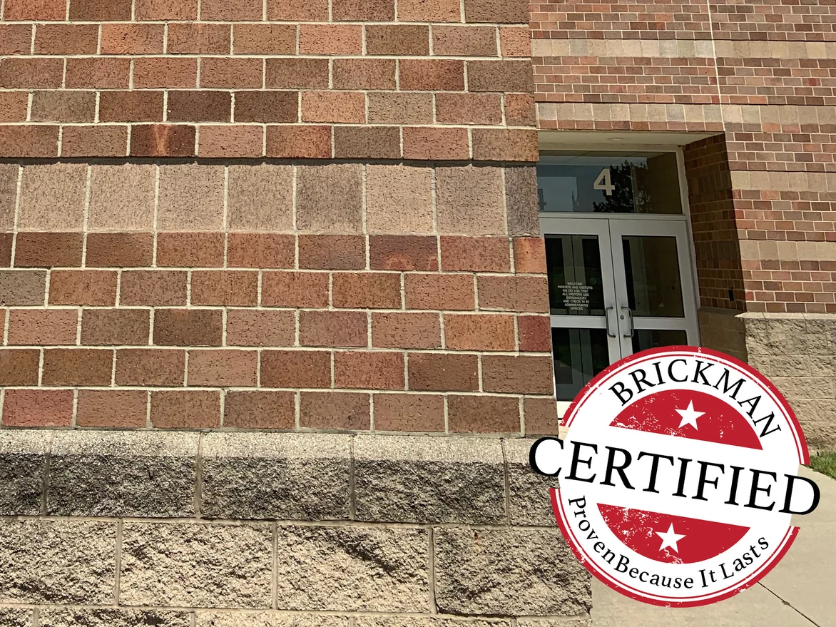 Close view of the school wall in 2019 beside a numbered entrance, the large square units sitting inside the red and brown range of the brick around them