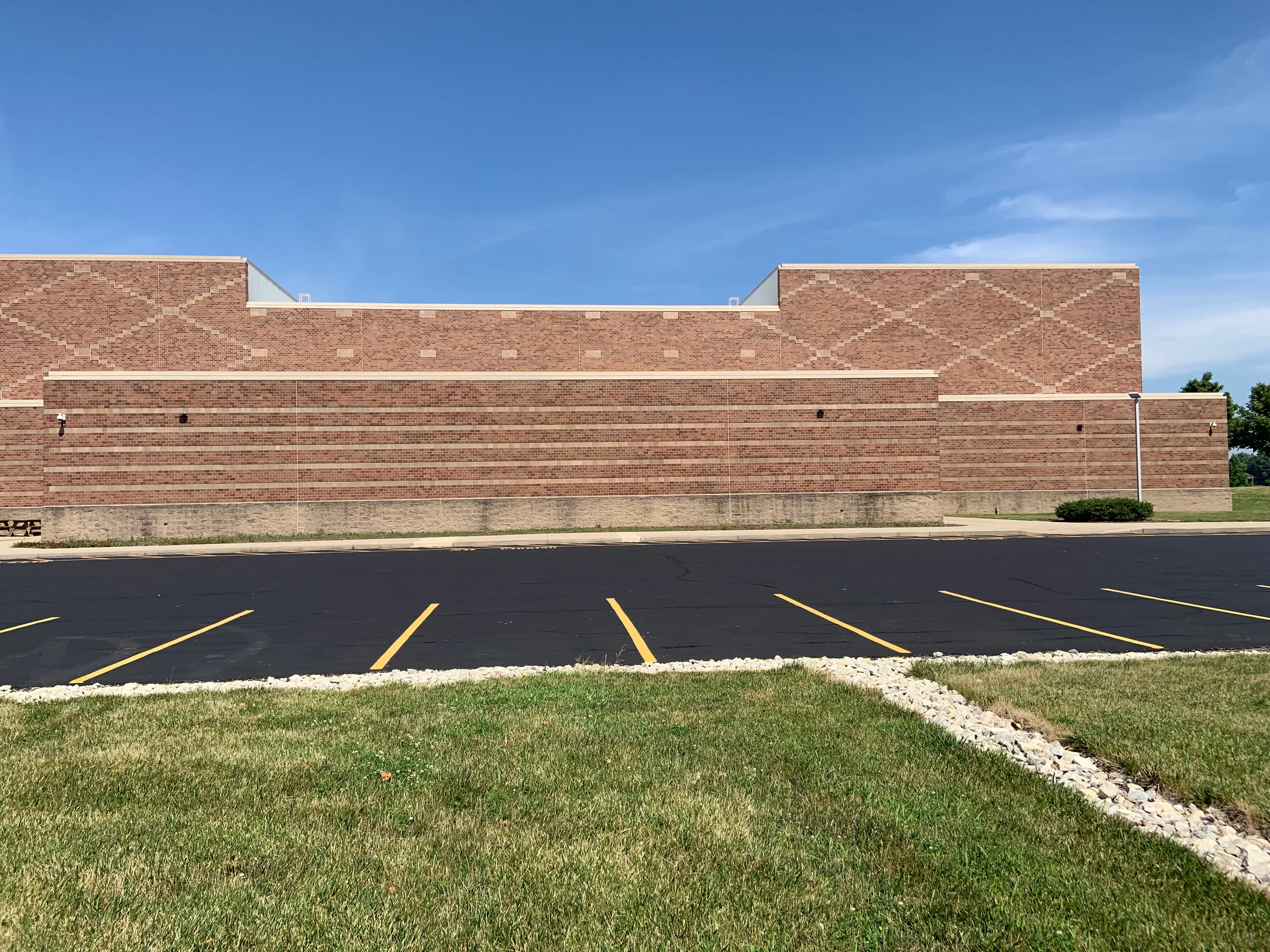 A long school elevation in 2019 seen flat on across the car park, the square units forming a diamond pattern in the upper band of brick