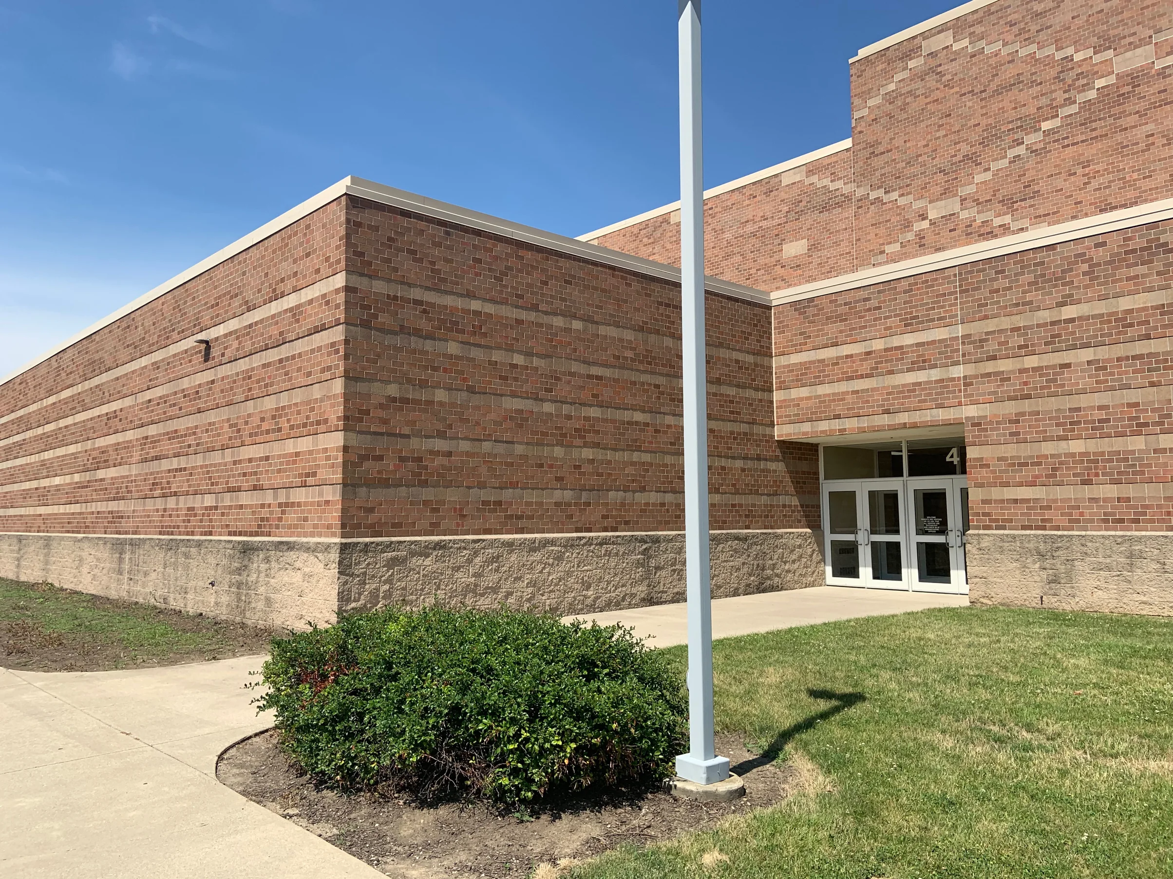 The corner of the school in 2019 with an entrance under the taller block behind it, the brick reading as one red and brown range along both walls