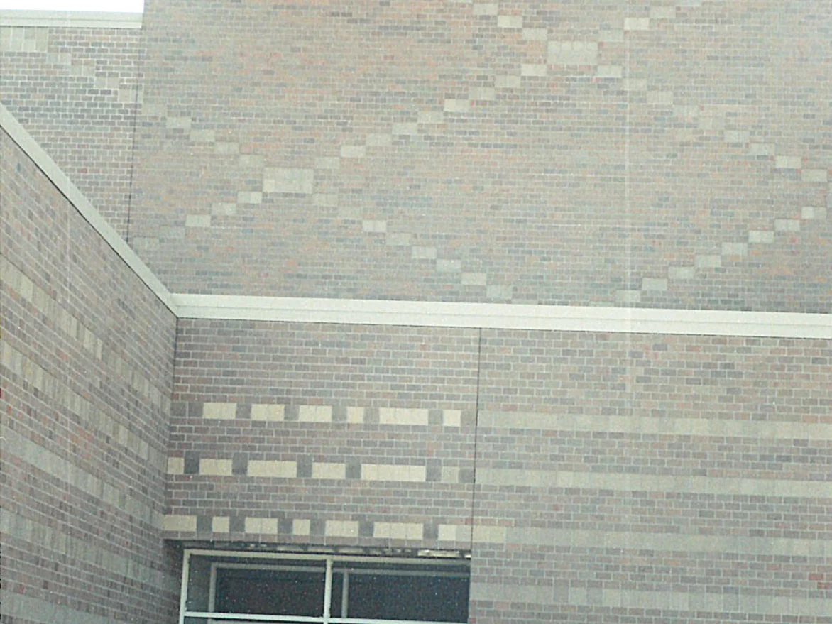 A school wall in 2000 with pale cream square units set through the red and grey brick, several shades lighter than everything around them