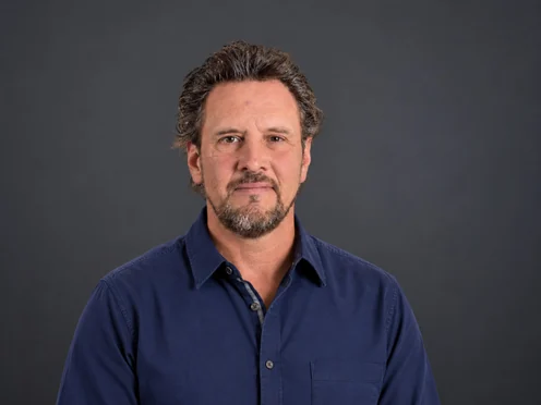 Richard Moore in a navy button-up shirt against a dark grey studio backdrop