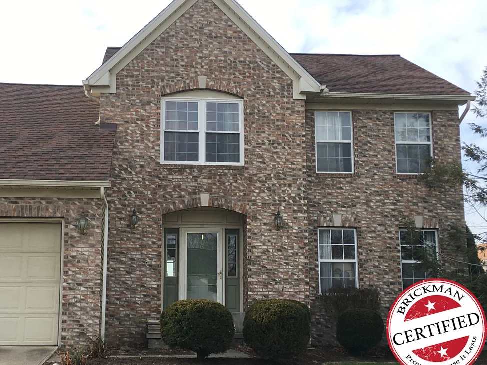 The front of the house in Brecksville in 2021, tan and brown blended brick across the gable and both stories, with the certification stamp in the corner