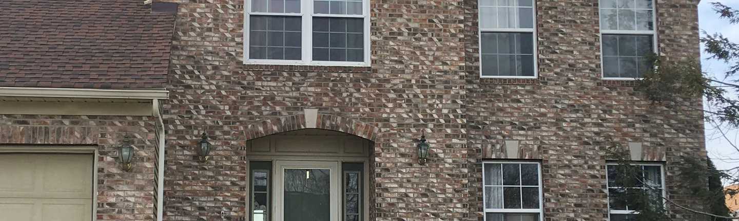 The front of the house in Brecksville in 2021, the gable and both stories reading as one blended range of tan and brown brick