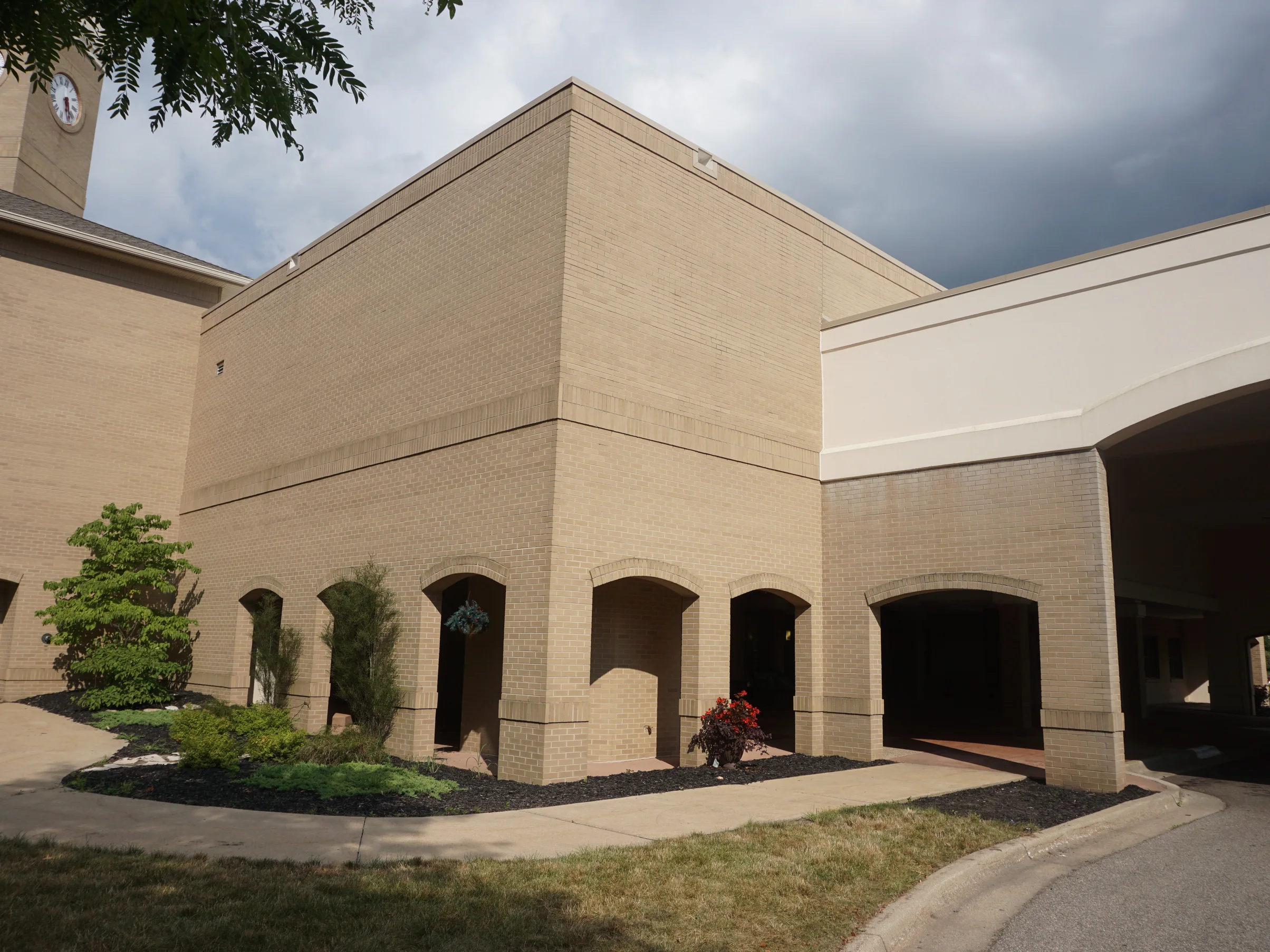 The arcaded entrance at Bronson Place in 2019, the brick corner, the arch heads and the wing beyond all one even cream