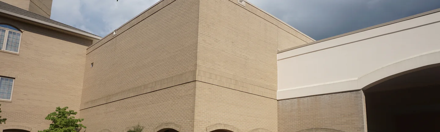 Bronson Place in 2019, the brick on the corner and the arcade reading as one even cream