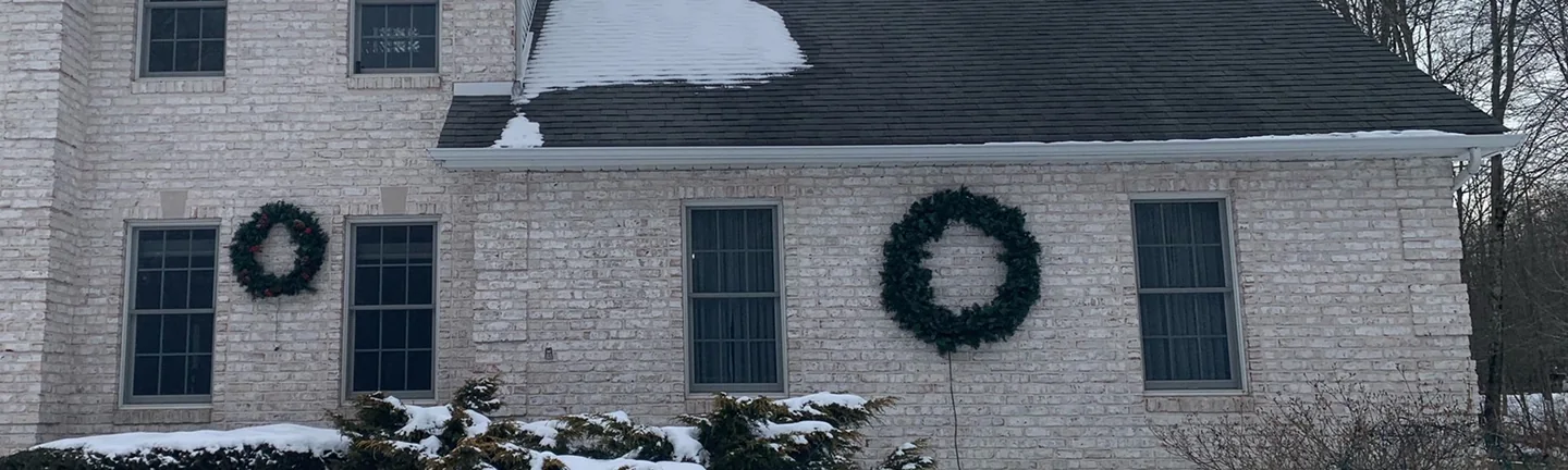 The front of the Brookfield home in 2021, white tumbled brick across the two-story block and the one-story wing under a snow-covered roof