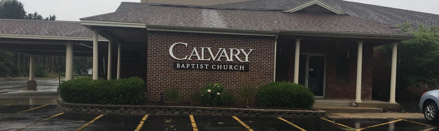 The entrance wing of the church in 2019, red brick under a drive-through canopy on round white columns, with the church's name sign on the wall