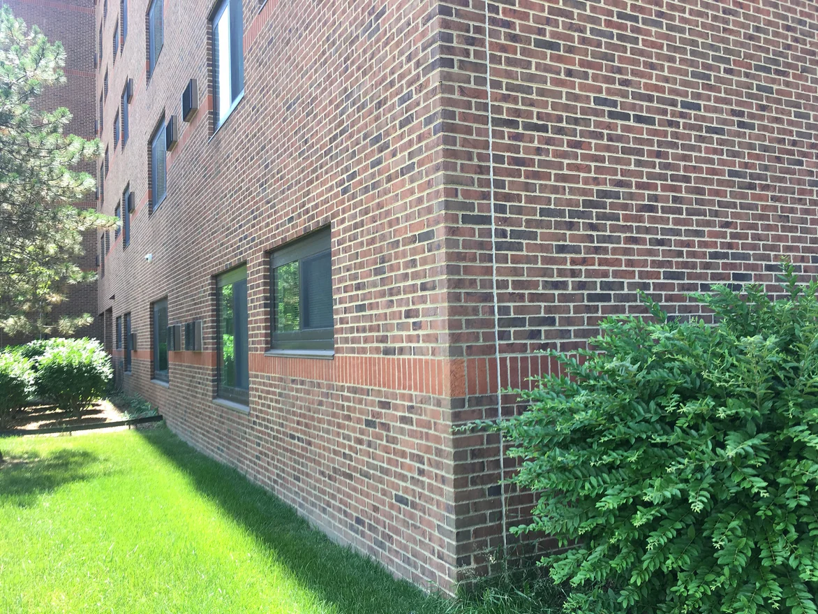 Brick at close range in 2019, reds, browns and near-blacks reading as one blend with an orange accent course running across the corner