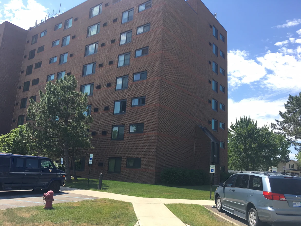 An outside corner of the high rise in 2019 against a clear sky, both faces carrying the same brick color