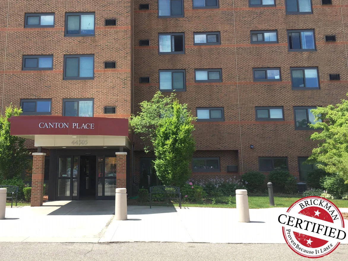 The entrance canopy in 2019 below an even red-brown brick elevation, with a certification stamp in the corner of the photograph