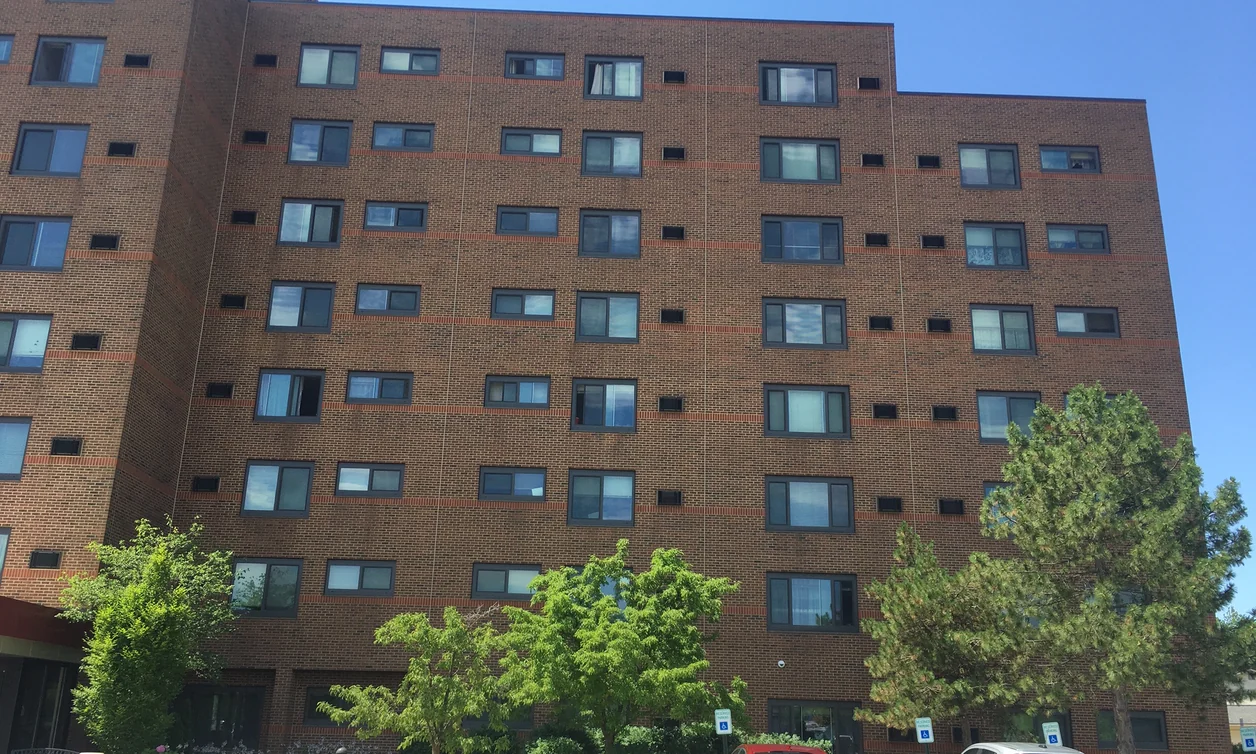 A brick high rise in Canton, Michigan in 2019, its two runs of brick reading as one wall twenty-five years after staining