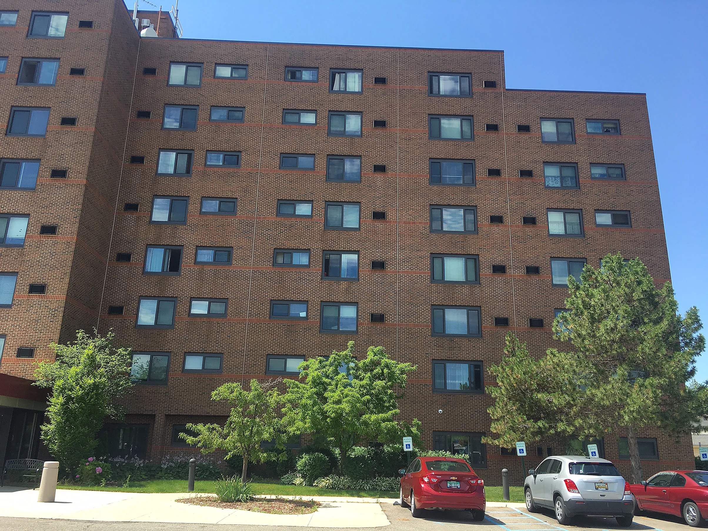 The full elevation in 2019, the brick reading as one even red-brown from the parking area to the roofline