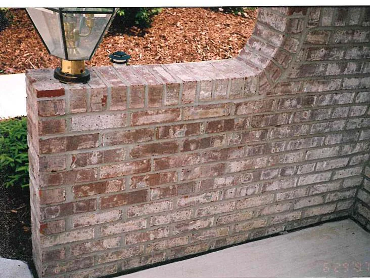 A low brick garden wall with a brass lantern on its pier in June 1997, dark red units scattered through pale cream ones, the camera date printed in the corner