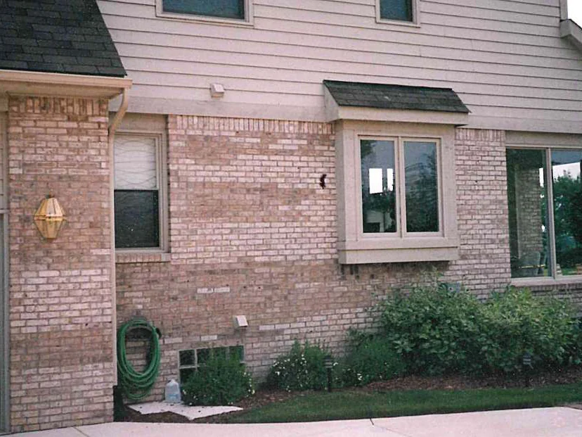 The side of the house in 1997 from the garage to the bay window, pale and dark patches of brick running in uneven bands across the wall under the siding