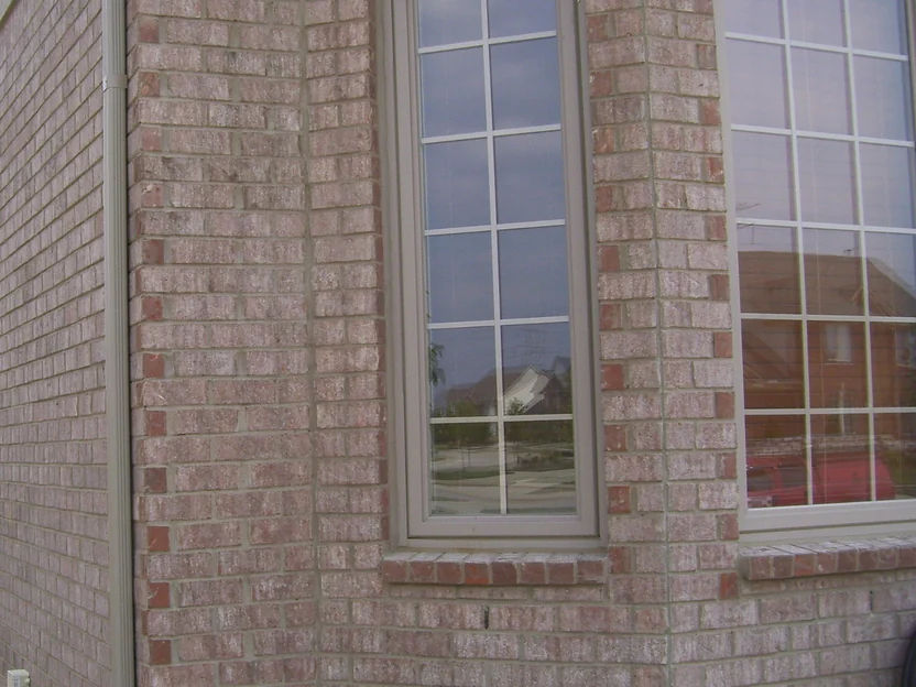 The bay window corner in close-up in July 2010, orange header bricks turned end on running up both piers and along the sill course