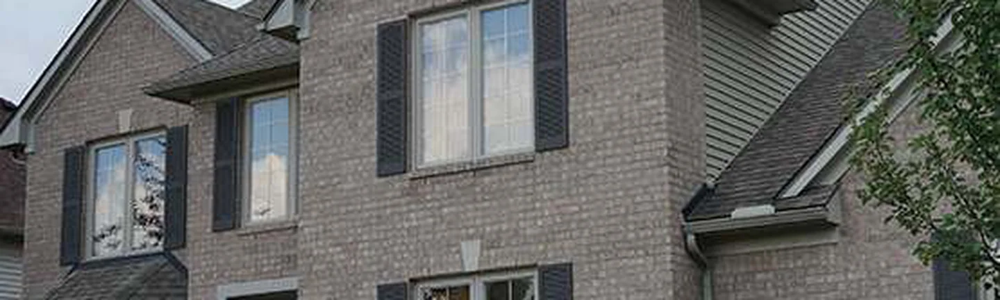 The front of the Canton house in 2020, cream and tan brick running unbroken across the gable, the bay window and the entrance