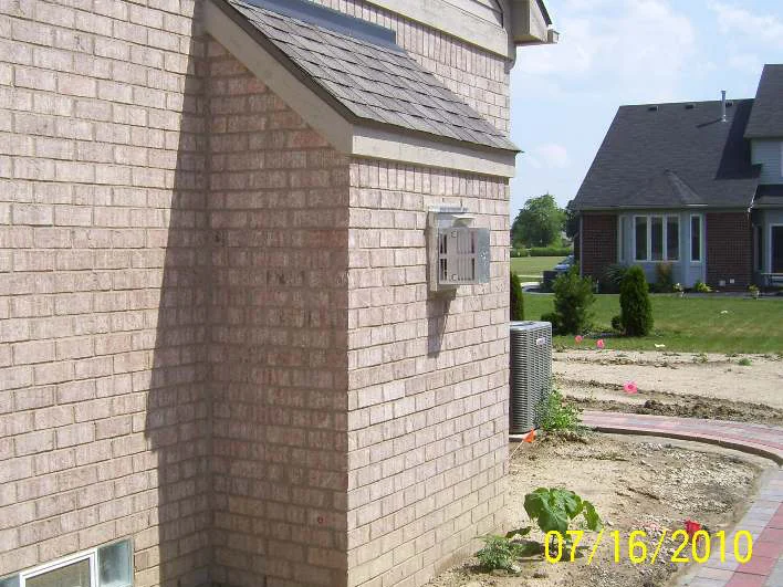 The same rear corner a day later, the headers lightened into the wall, an air conditioning unit and a new paver walk below
